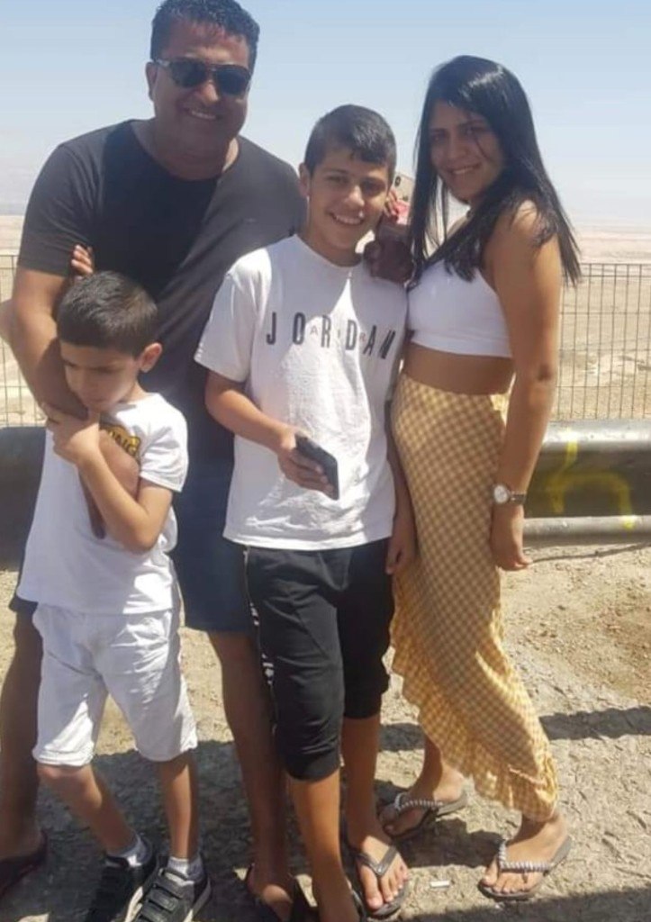 Kim smiling with her family on a sunny day outdoors at a desert lookout