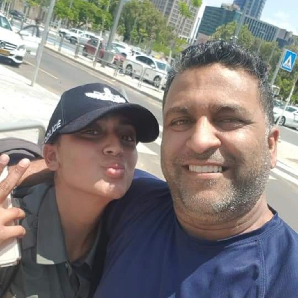 Kim in her police cap and uniform playfully posing with a smiling man on a sunny city street